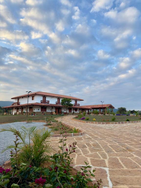 Un edificio su un campo con un cielo nuvoloso di Hotel Palais Barichara a Barichara