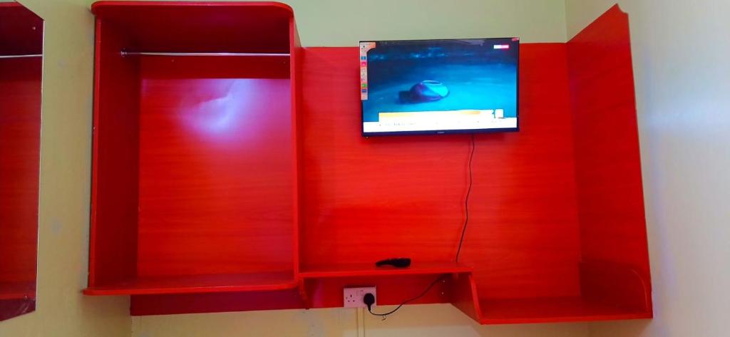 a red wall with a tv in a room at Njata Country House in Oljoro Orok