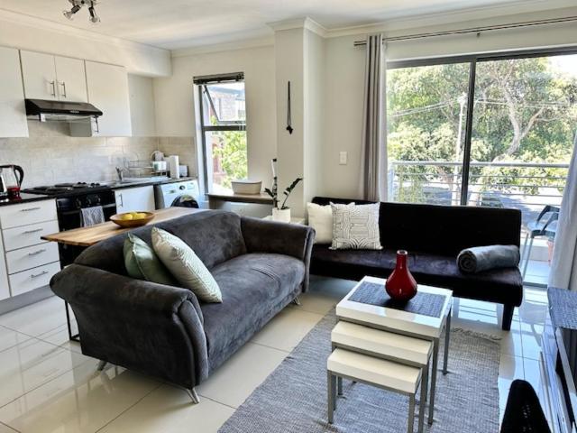 a living room with a couch and a kitchen at Cozy Rondebosch Apartment in Cape Town