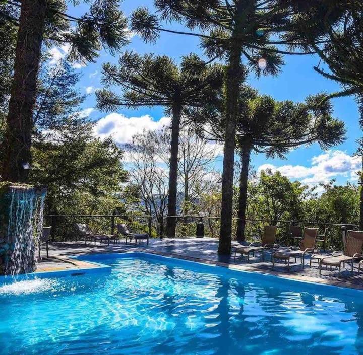 a large swimming pool with trees in the background at Suite Confort - Gramado Wish Serrano in Gramado