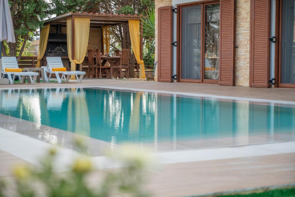 a swimming pool in front of a house at Peroulis Villa in Laganas
