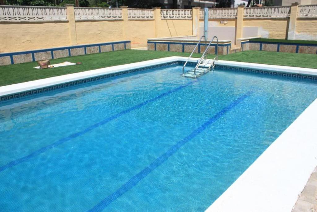 uma piscina com uma cadeira no meio dela em Apartamento ALOHA BABY a 2 calles del Mar em Sant Salvador