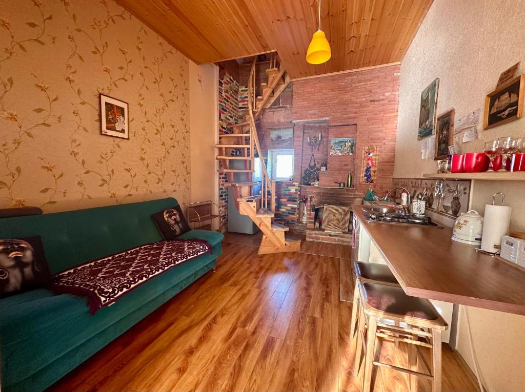 a living room with a green couch and a kitchen at Heart of Old Tbilisi Apartments in Tbilisi City