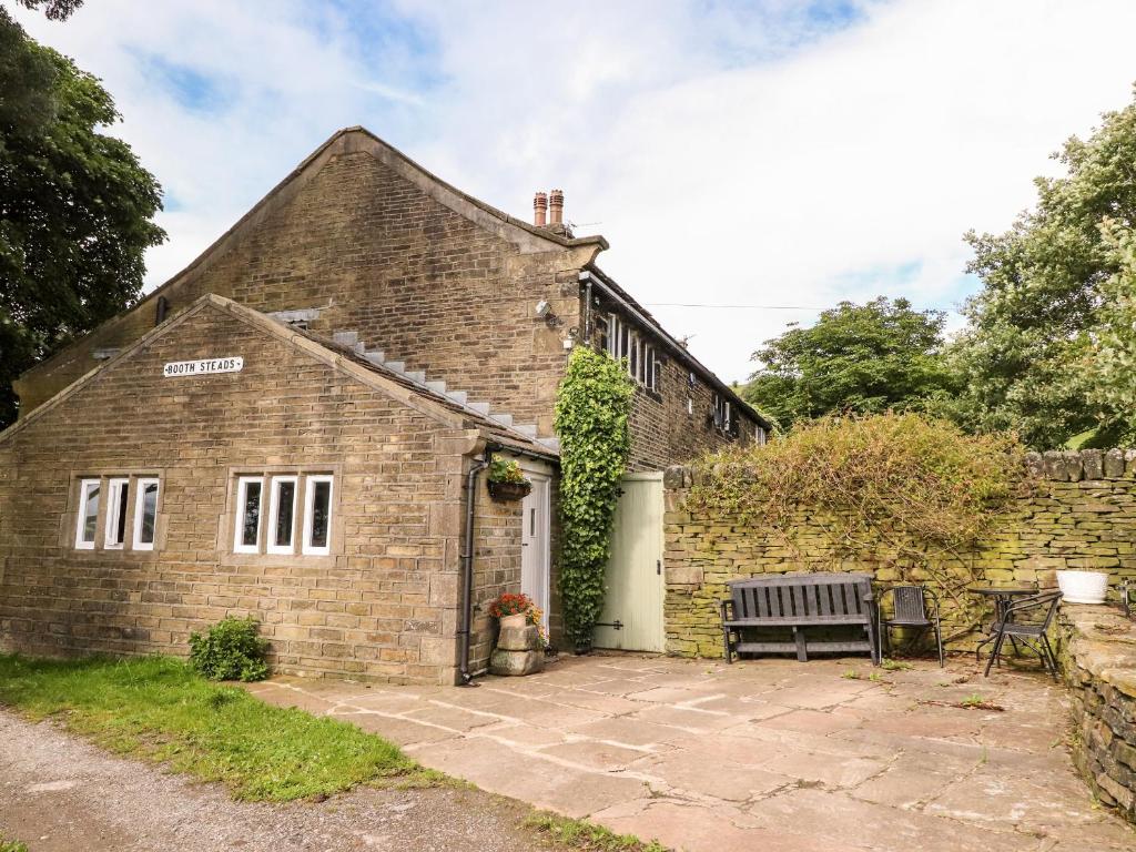 een oud bakstenen huis met een bankje ervoor bij Boothsteads Farm Cottage in Halifax