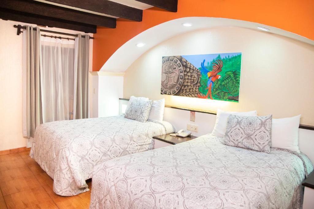 a hotel room with two beds and a painting on the wall at Hotel Catedral in San Cristóbal de Las Casas