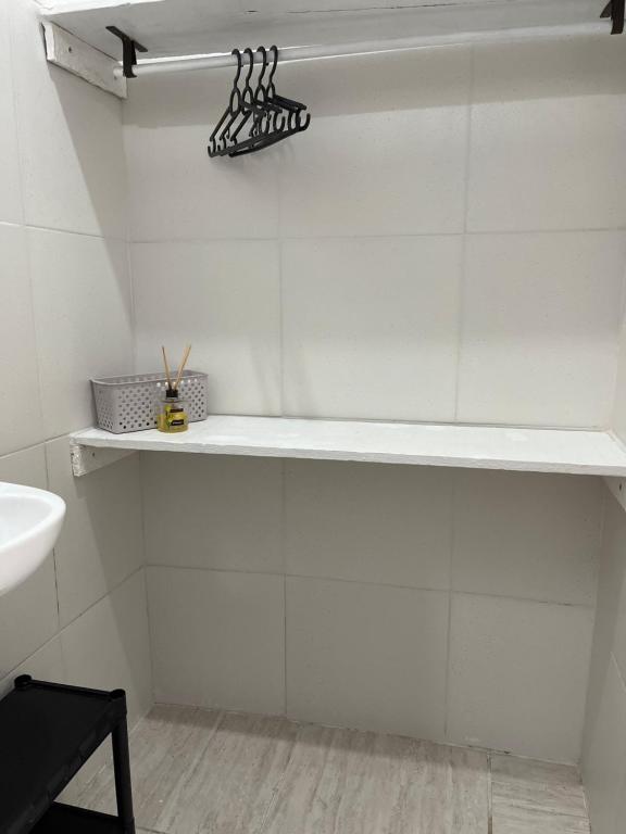 a white bathroom with a shelf on the wall at Pousada Suítes Sete Mares in Guarujá