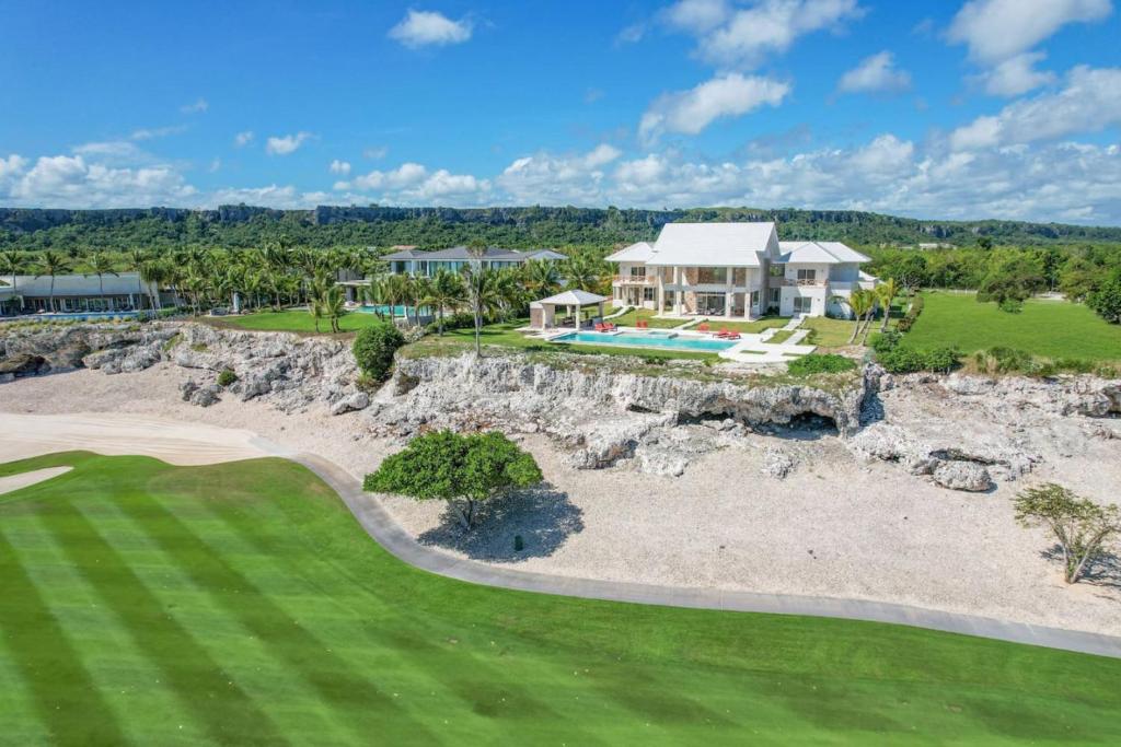 an aerial view of a house with a rock wall and a golf course at Villa Okyanus with Fantastic Ocean View Chef Butler Maid Golf Cart in Punta Cana