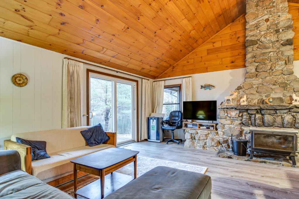 a living room with a couch and a stone fireplace at Cozy Thompson Lake Cabin with Boat Dock and Launch 