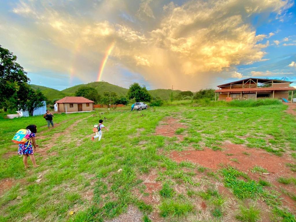 two children standing in a field with a rainbow in the sky at Espaço Amainar in Sobradinho