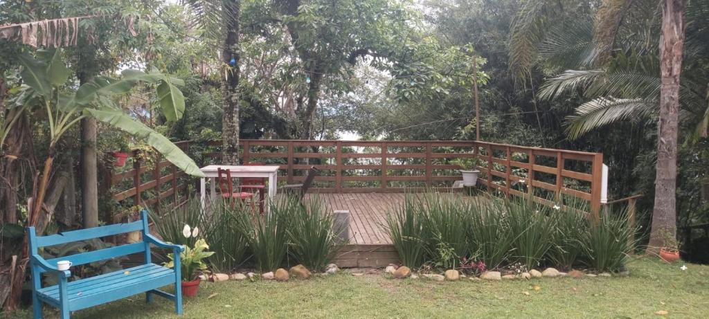 ein Holzdeck mit einer blauen Bank in einem Garten in der Unterkunft Chalés com vista para Lagoa de Ibiraquera in Imbituba