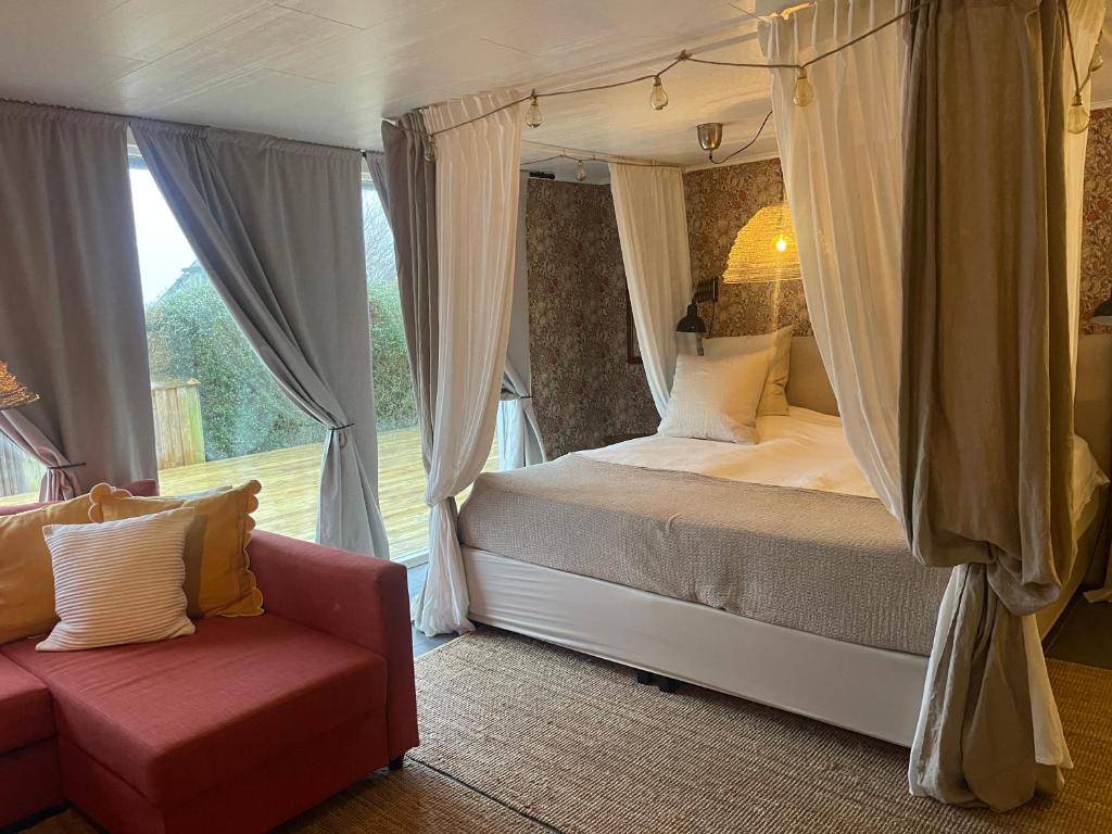 een slaapkamer met een bed, een bank en een raam bij Pia’s Country House in Båstad