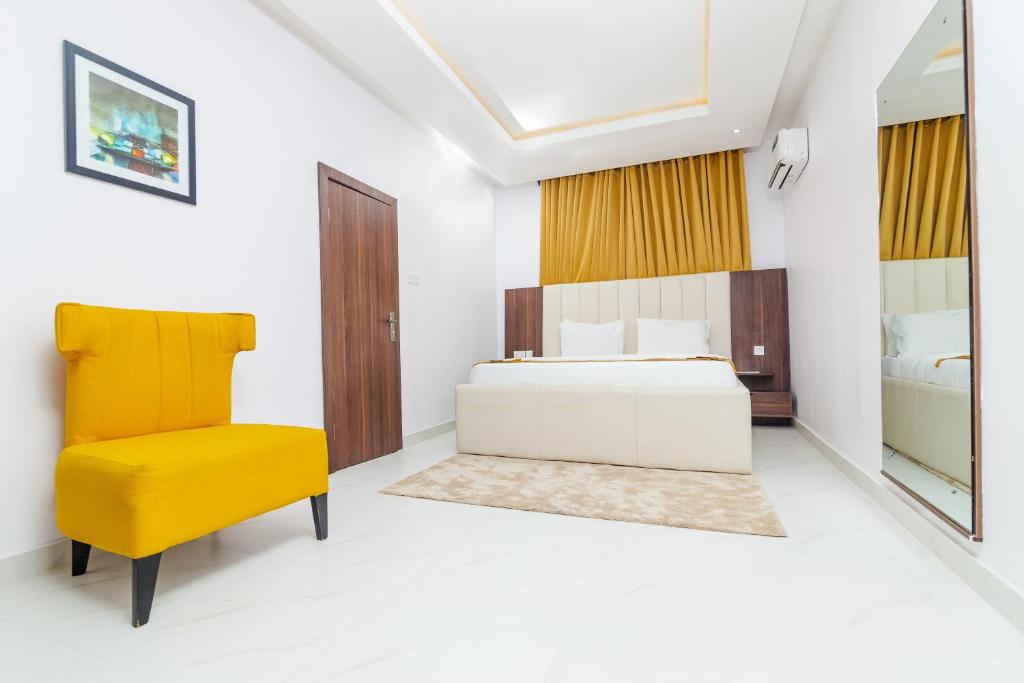 a bedroom with a bed and a yellow chair at LA FIFTHIN VILLA in Lekki