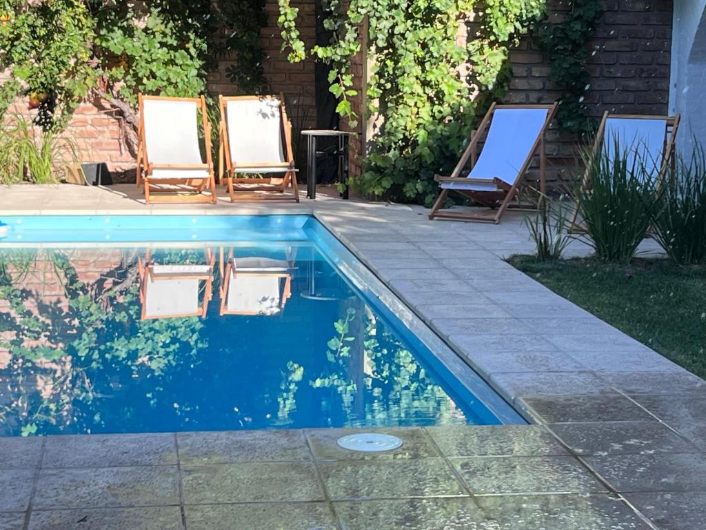 ein Pool mit zwei Gartenstühlen daneben in der Unterkunft Oeste suites in Mendoza