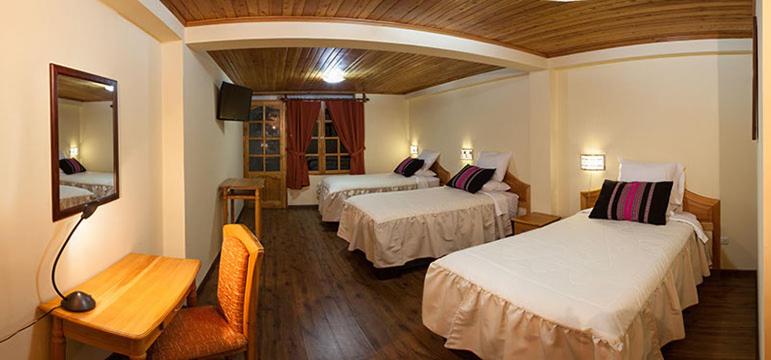 a hotel room with two beds and a television at Maimara Hotel in Huaraz