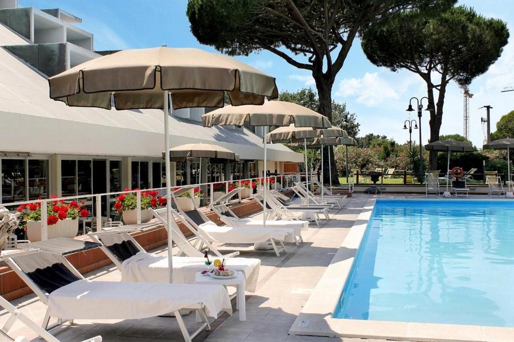 um grupo de cadeiras e guarda-sóis ao lado de uma piscina em PFA Hotel La Darsena - Follonica em Puntone di Scarlino