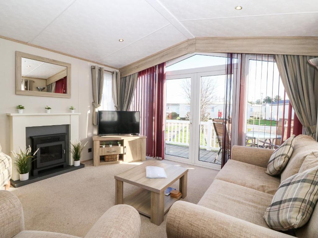 a living room with a couch and a television at Snape Lodge in Abergele