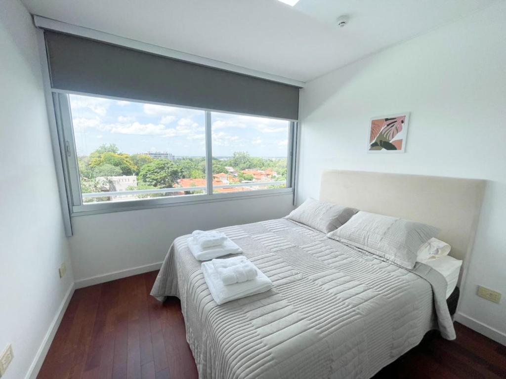 a bedroom with a white bed with a large window at Hermoso departamento en Skytower in Asuncion