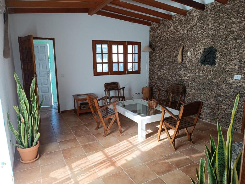 Habitación con mesa, sillas y pared de piedra. en Casa de Familia Felipe y Martin, en Tías