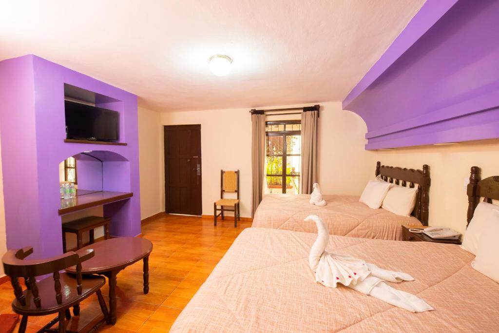 1 dormitorio con 3 camas y techo púrpura en Hotel D’Monica, en San Cristóbal de Las Casas