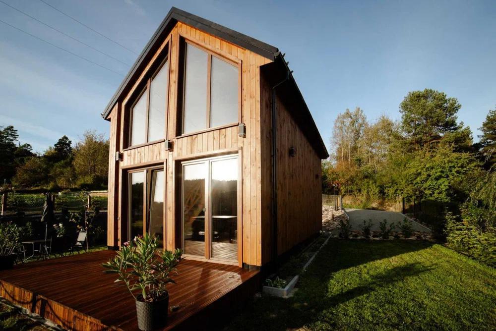 a small wooden house with large windows in a yard at UKOISKO Bieszczady in Ropienka