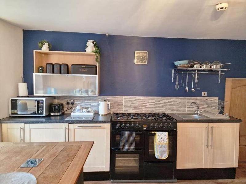 a kitchen with a stove and a blue wall at The kings in Denbigh