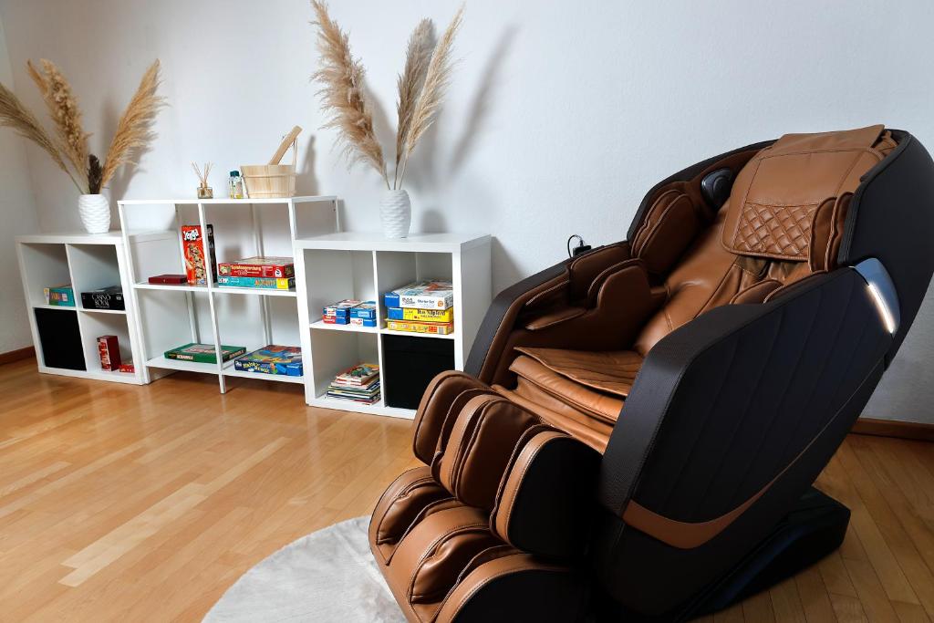 einen Ledersessel in einem Wohnzimmer mit Regalen in der Unterkunft Vallhouse - Massage, Sauna, Darts, Switch & mehr in Vallendar