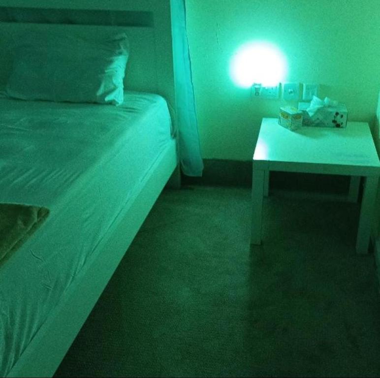 a room with a bed and a table with a light at YOUR HOME in Dubai