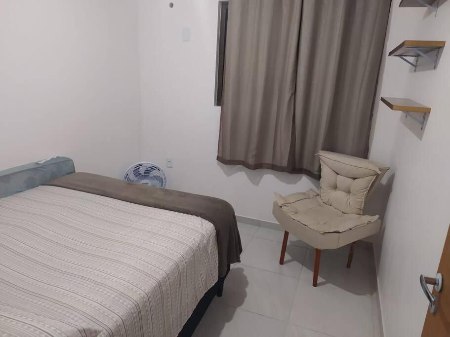 ein Schlafzimmer mit einem Bett, einem Stuhl und einem Fenster in der Unterkunft Apto familiar c/ piscina, próx as praias reg Sul in João Pessoa