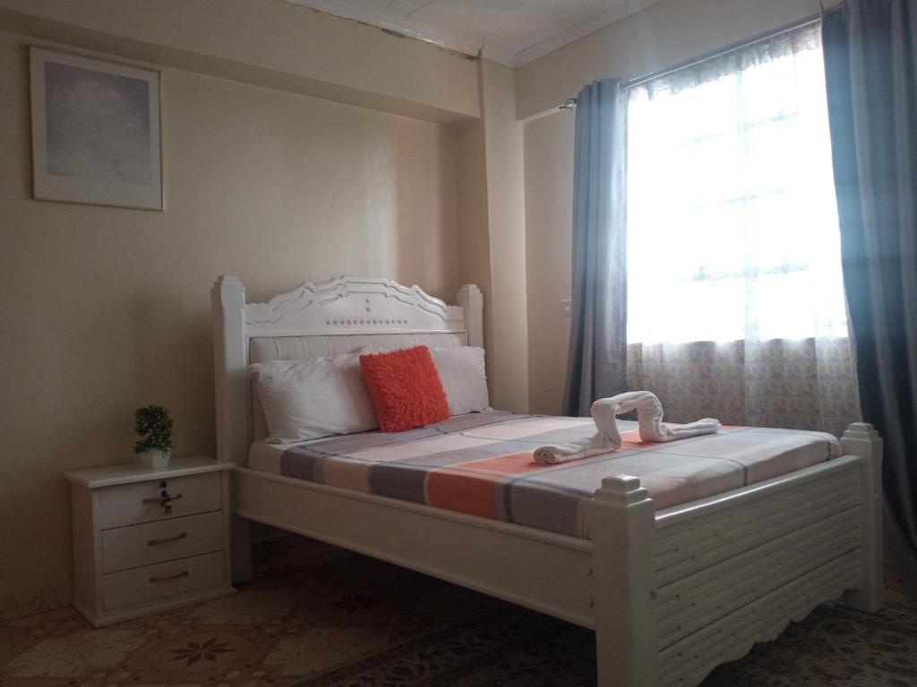 a bedroom with a white bed and a window at MT. KENYA PALACE in Nyeri