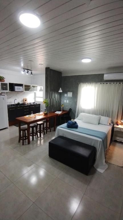 1 dormitorio con cama, mesa y cocina en Studio Girassol, en Florianópolis