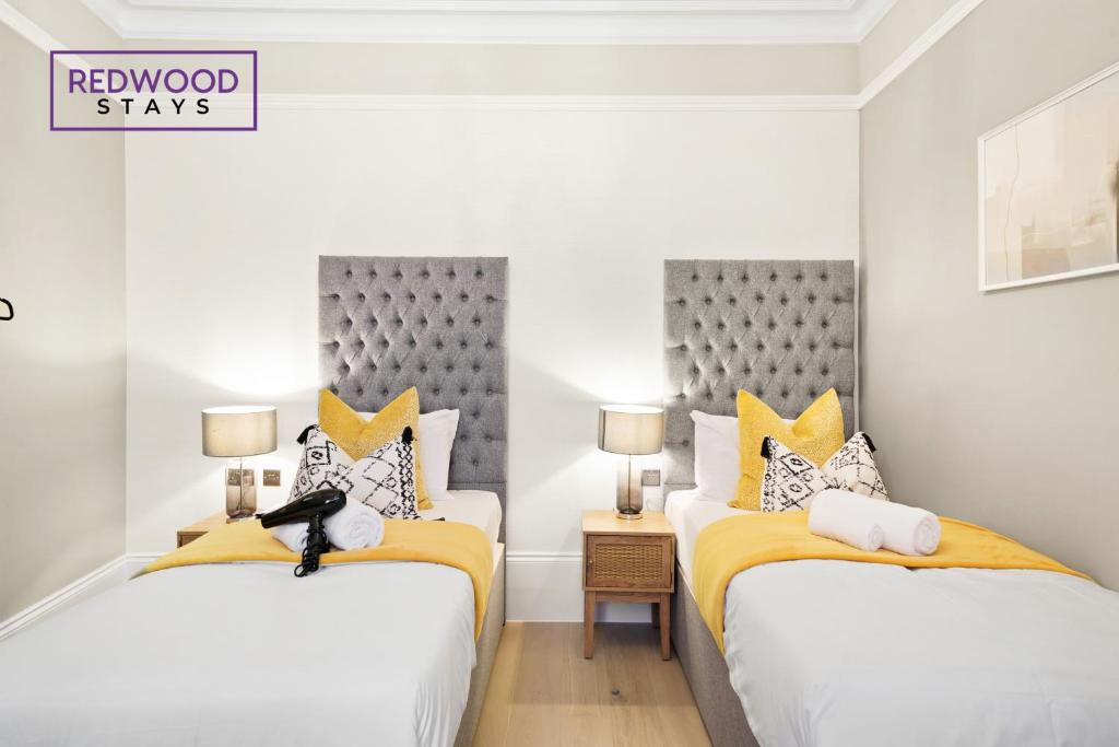 two beds in a white room with yellow and gray pillows at Premium 1 Bed 1 Bath Apartments For Corporates By REDWOOD STAYS in Reading