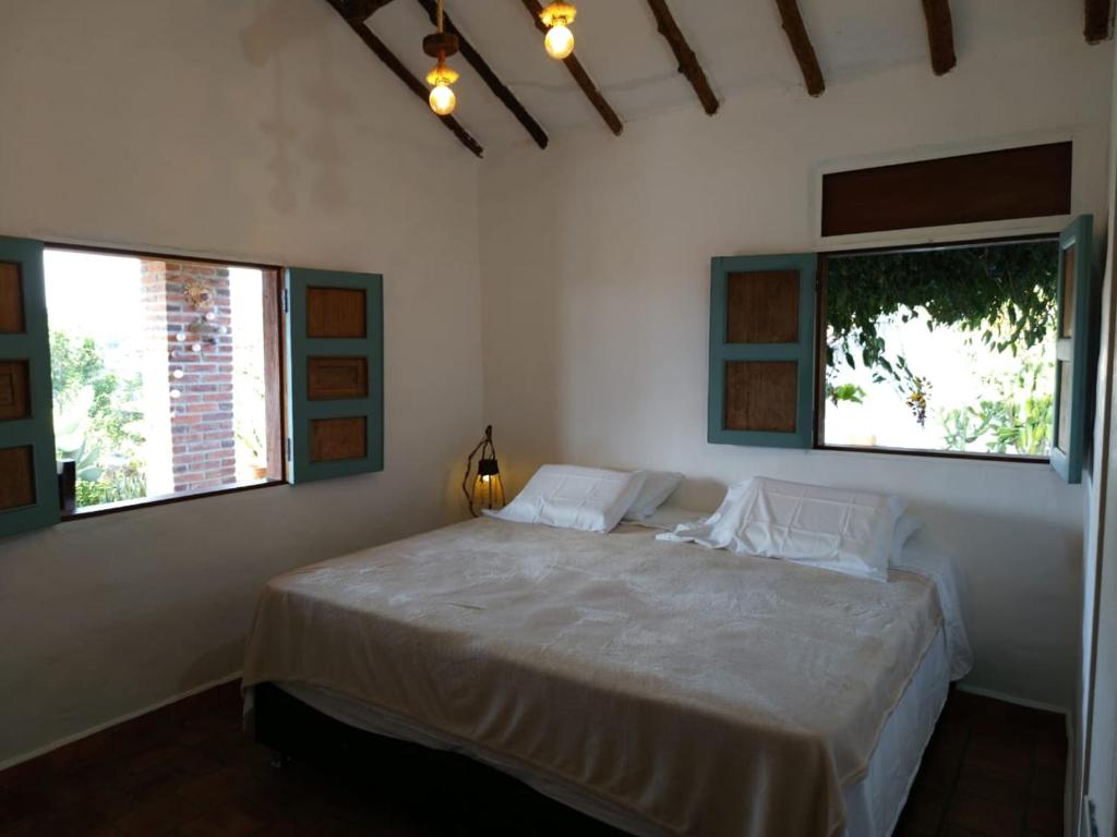1 dormitorio con 1 cama grande y 2 ventanas en Casa Castañeto Barichara en Barichara