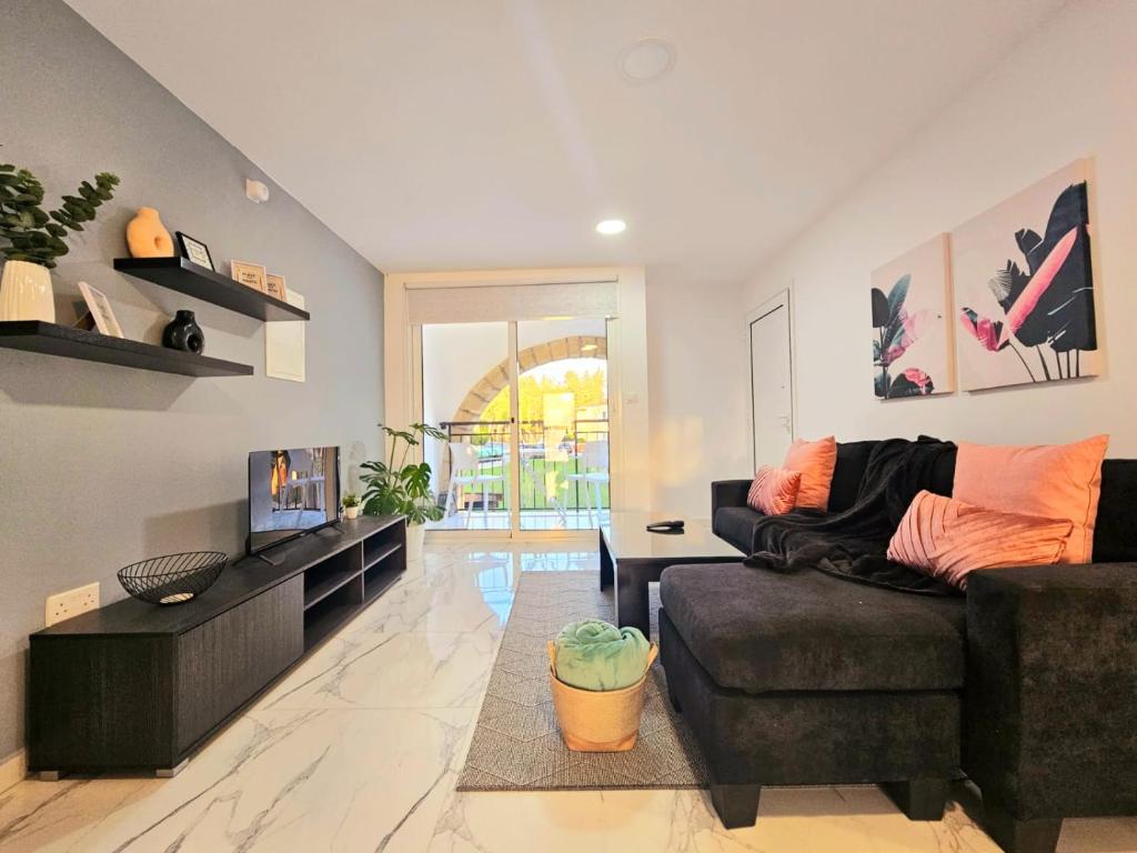 een woonkamer met een bank en een tv bij 1BD Beach Apartment in Paphos City