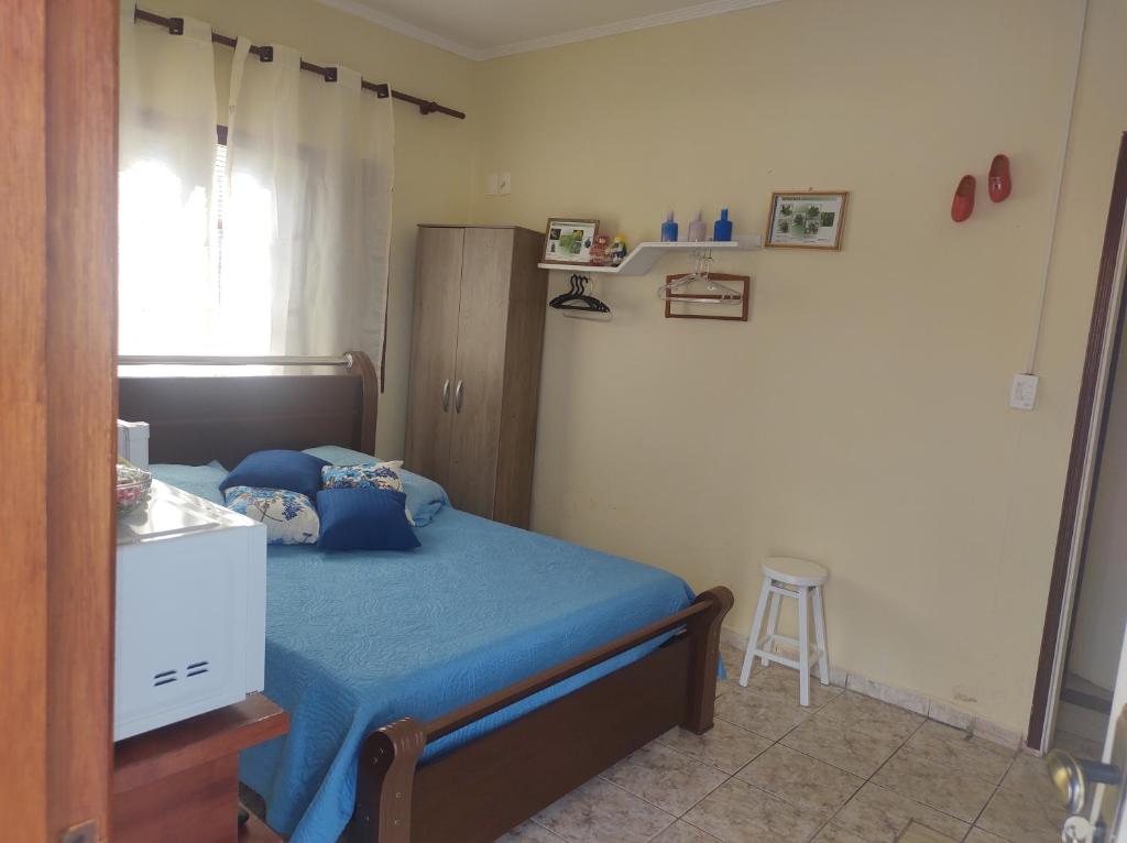 1 dormitorio con cama con sábanas azules y taburete en QUARTO CONFORTAVEL COM GARAGEM en Holambra