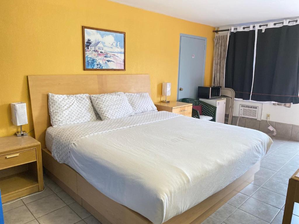 a bedroom with a large white bed with yellow walls at Tides Inn at Stehli Beach in Locust Valley