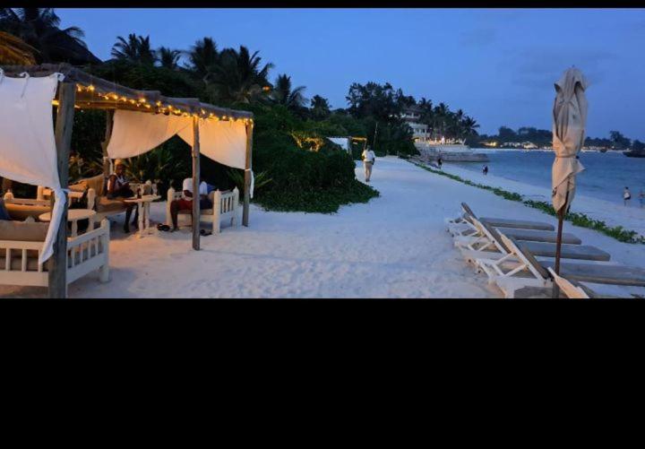 - une plage avec des tables et des chaises sur la plage dans l'établissement Bamburi mwembeni, à Mombasa