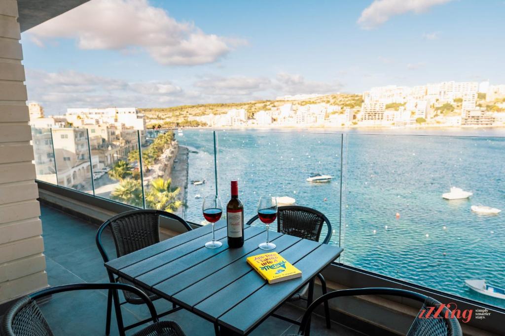 a table with wine glasses and a view of the water at Seaside Magic From a Stunning Apartment in St. Paul's Bay