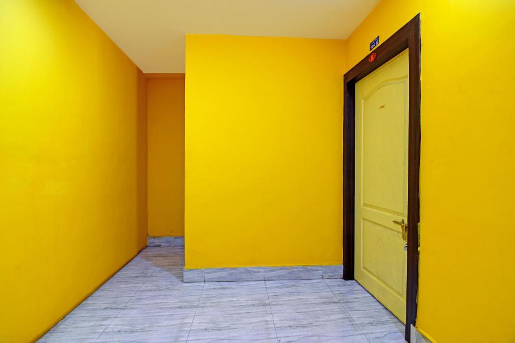 an empty room with a yellow wall and a door at OYO Shibani & Suhani in Bārang