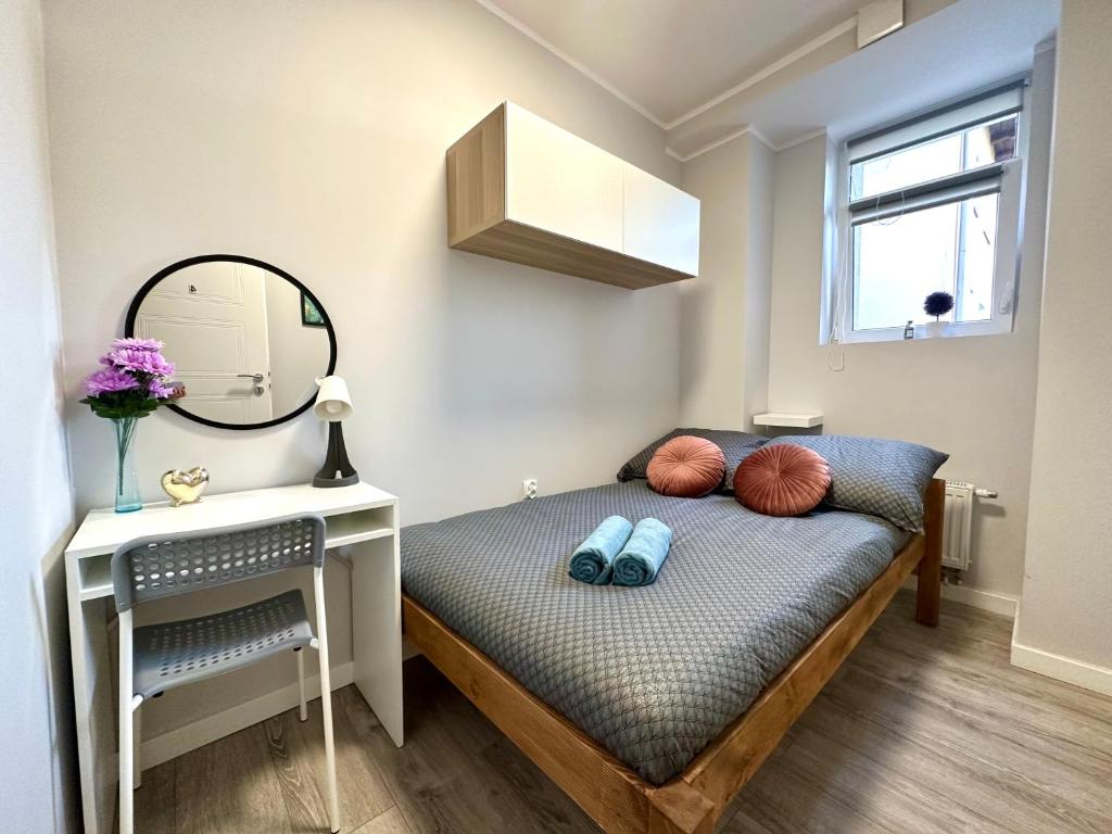 a small bedroom with a bed and a mirror at MMRent Warmly Room in Gdańsk