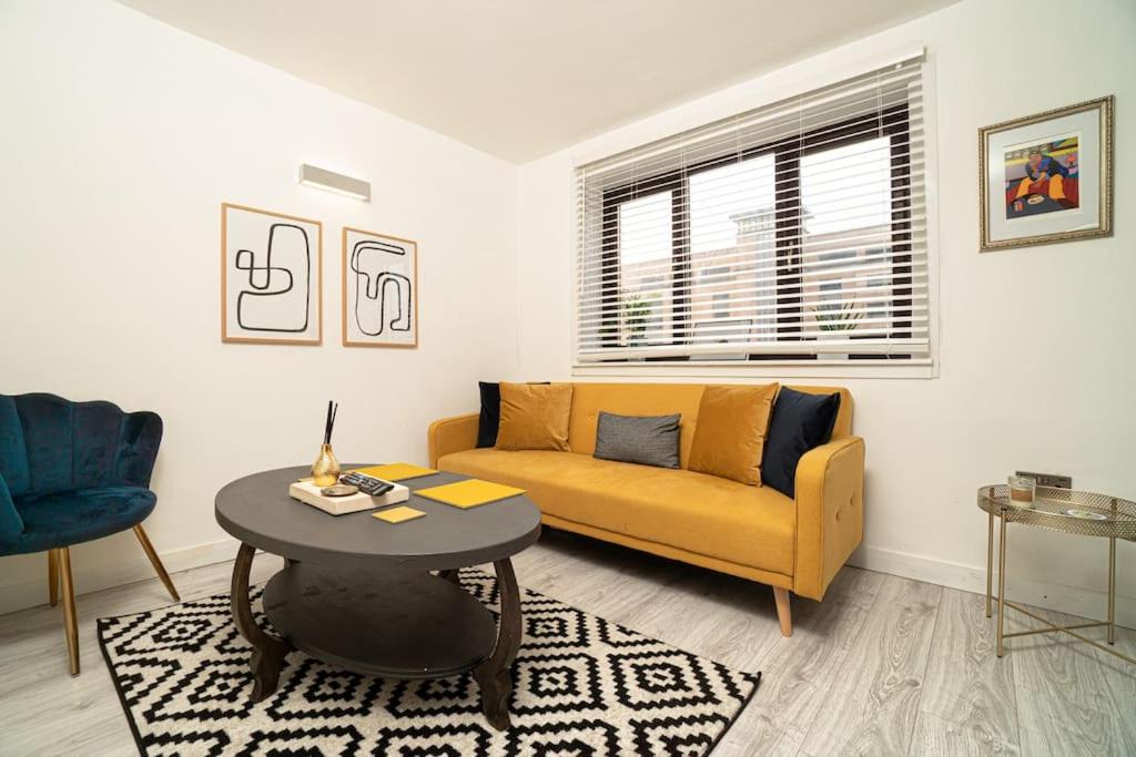 uma sala de estar com um sofá amarelo e uma mesa em Stylish City Pad with Free Private Parking em Glasgow