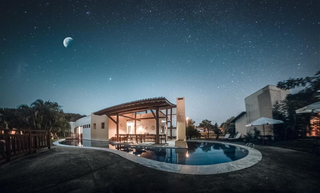 una casa con piscina por la noche con luna en Pipa ,Bosque da Praia Flat 21 en Pipa