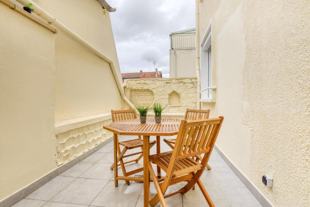 a small balcony with a wooden table and two chairs at Cozy Appart 4 Proche gare - Cozy Houses in Palaiseau