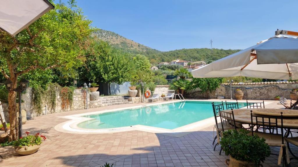 - une piscine avec une table et un parasol dans l'établissement Le rondinelle, à Castelnuovo Parano
