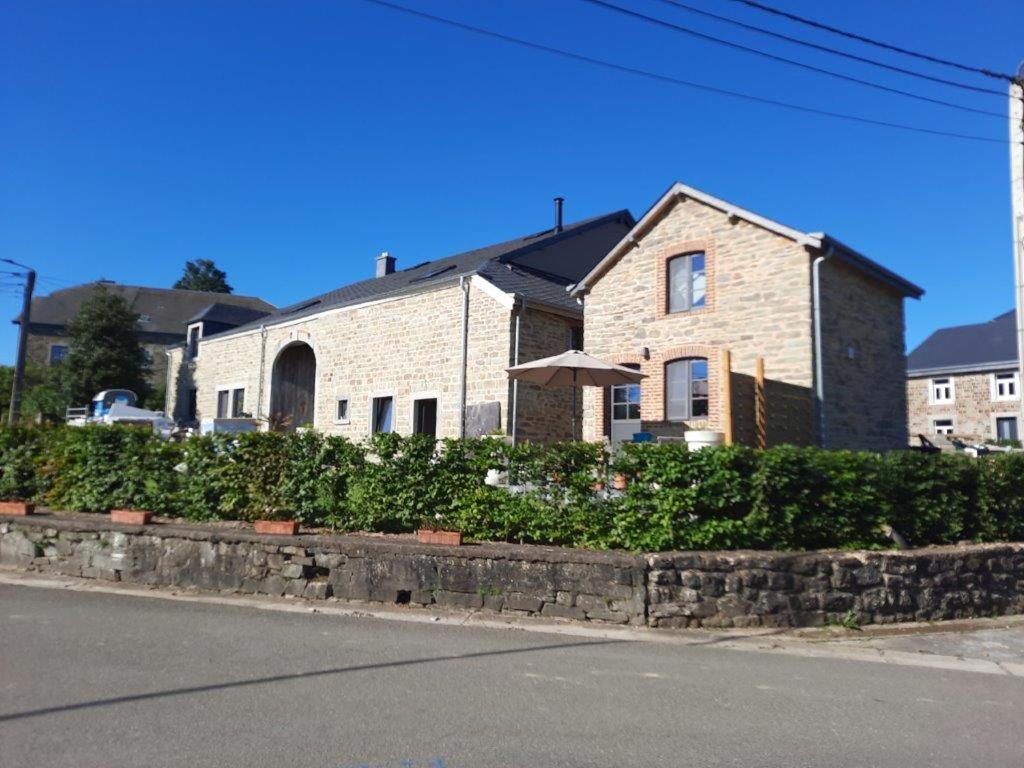 a brick house with an umbrella in front of a street at Le fournil de la Silentiaire in Opont
