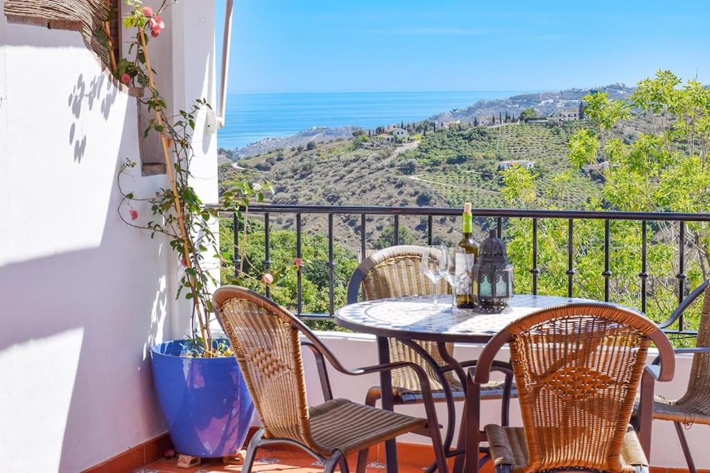 een tafel en stoelen op een balkon met uitzicht op de oceaan bij Apartamento Vista del Valle, Frigiliana 2 bedroom Apartment with great views HansOnHoliday Rentals in Frigiliana
