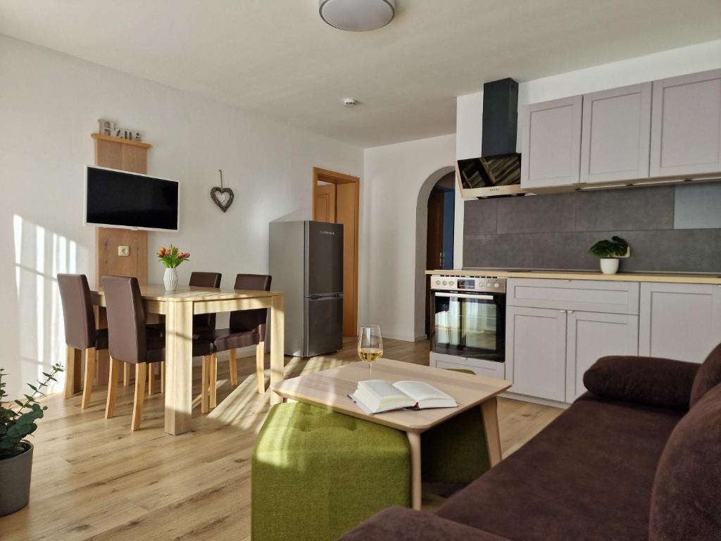 een keuken en een woonkamer met een bank en een tafel bij HoFer am Zeitberg Ferienwohnung Echelsbach in Bad Kohlgrub