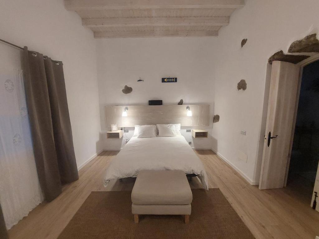 a white bedroom with a bed and a chair at Casa Ines in Guatiza