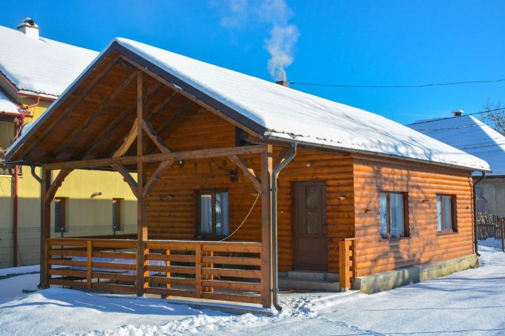 Cabaña de madera con techo cubierto de nieve en Căsuța Adelina, en Borşa