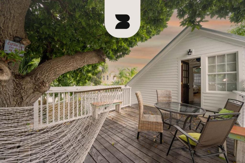 a hammock on a deck with a table and chairs at Traveler's Palm by Brightwild in Key West