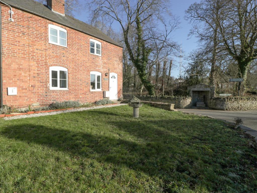 a brick house with a grass yard in front of it at 1 Tump Cottages in Hereford